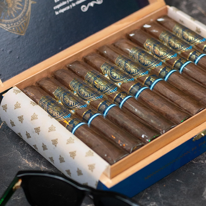 An open Dominium Primera cigar box with gold-patterned tissue paper